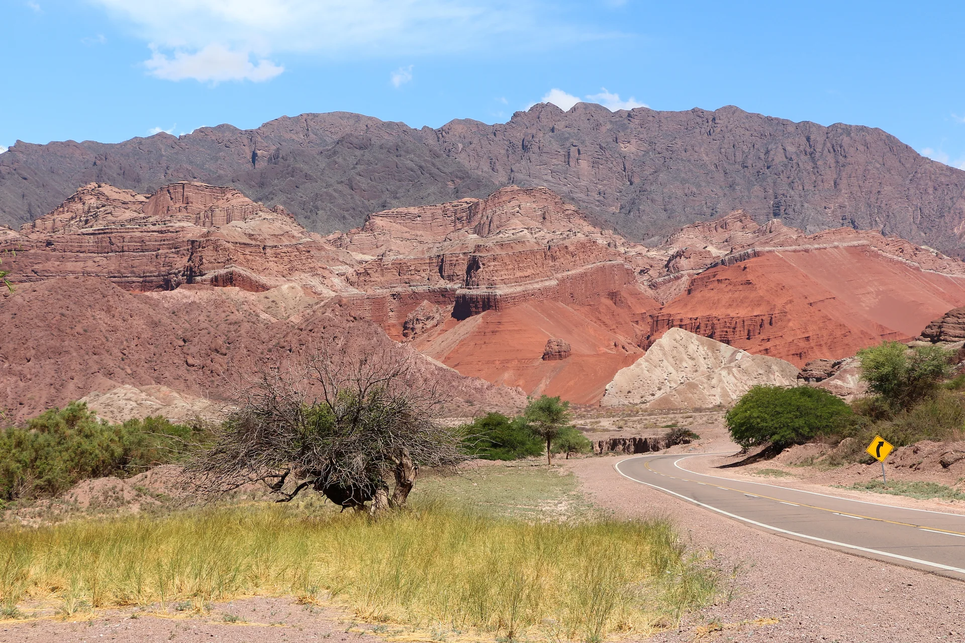 A winding regional road beneath colored rock formations in Quebrada de las Conchas