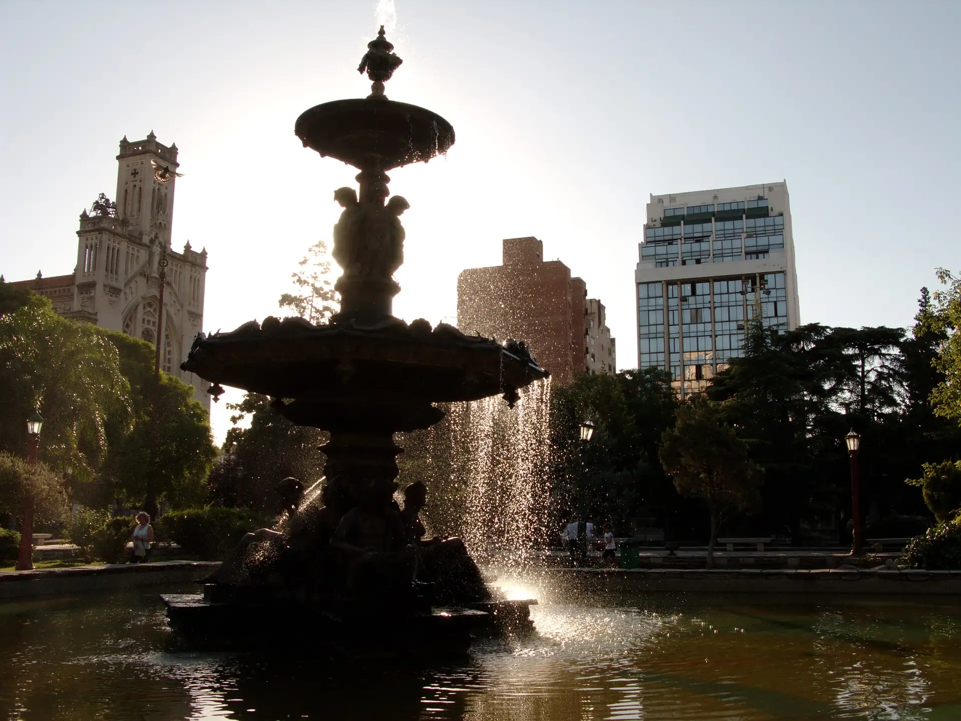 The fountain, trees and surrounding architecture in Plaza Colón, Córdoba, Argentina
