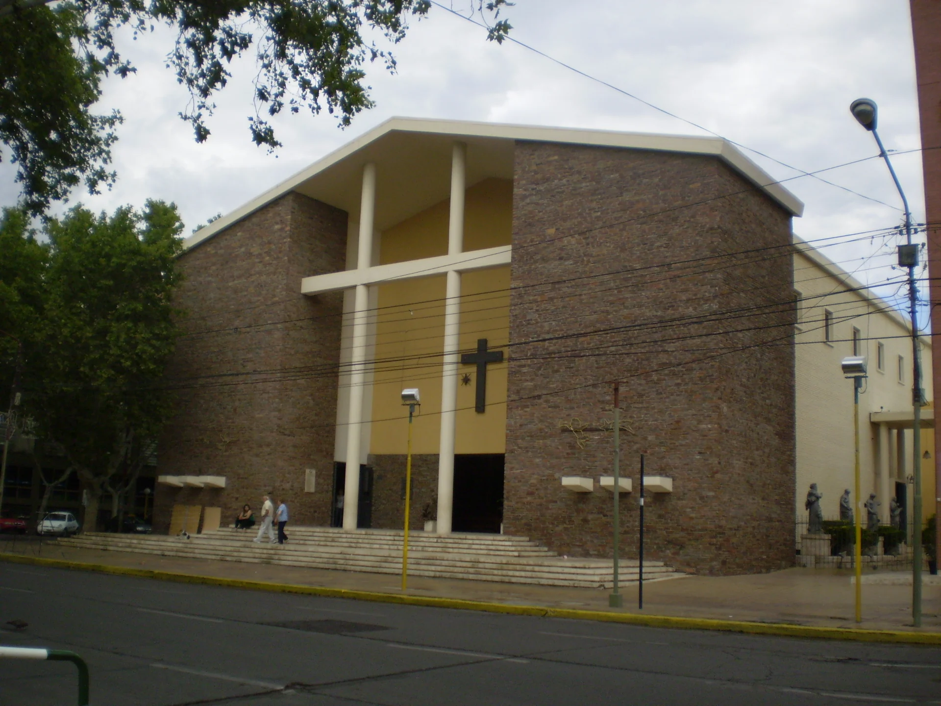 The brick facade, white cross and entrance steps of San Juan Bautista Cathedral