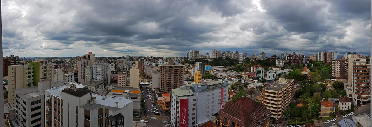 Bento Gonçalves city buildings, streets and trees beneath heavy clouds