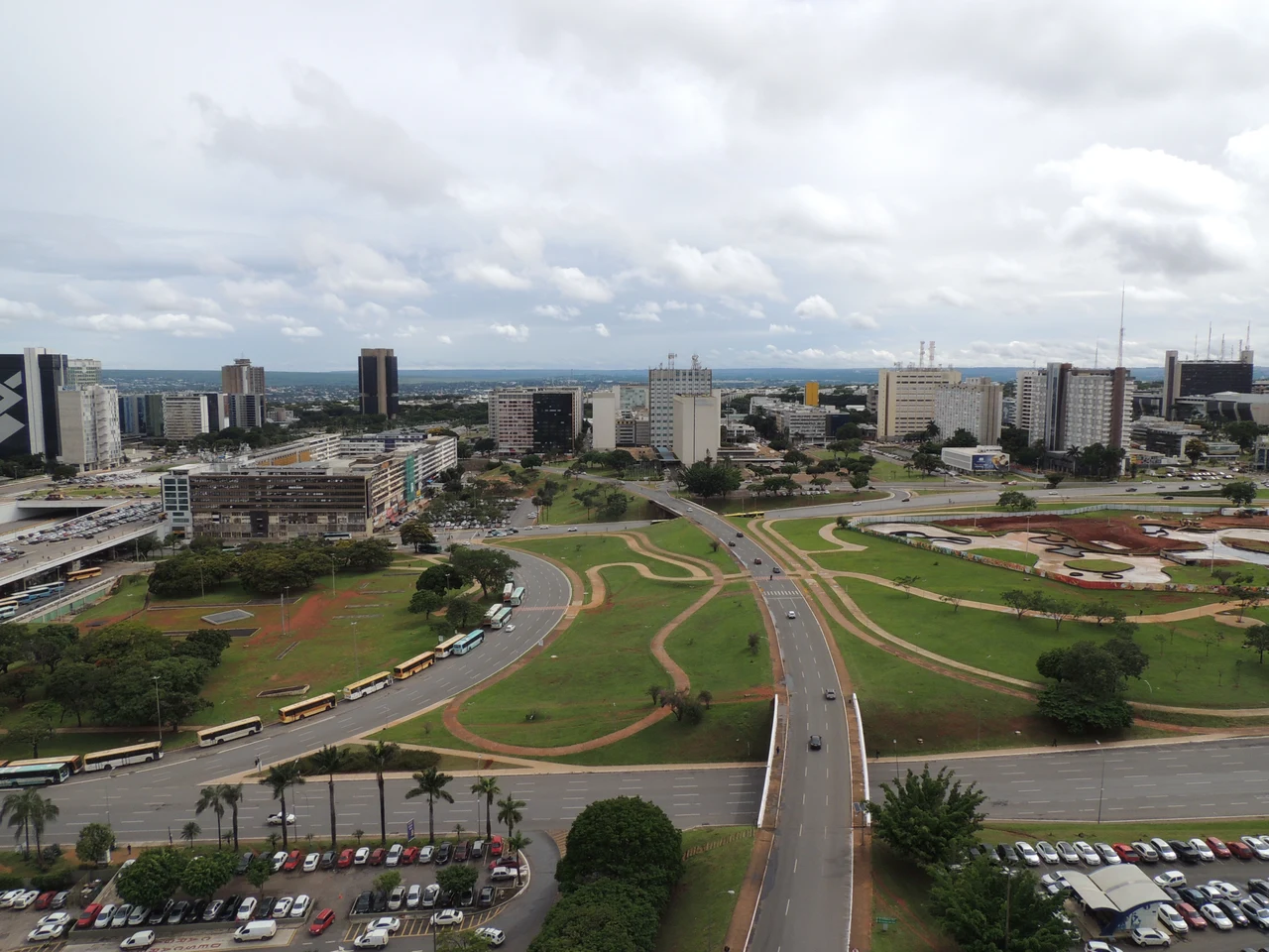 Historical central city view with office blocks, roads, buses, cars and lawns beneath clouds