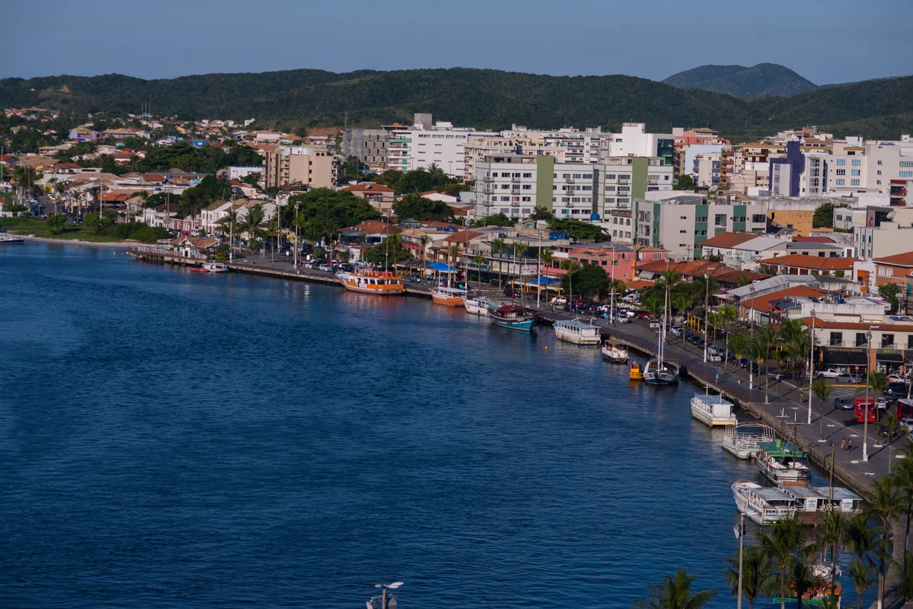 Boats in Cabo Frio below green hills and buildings with tiled roofs