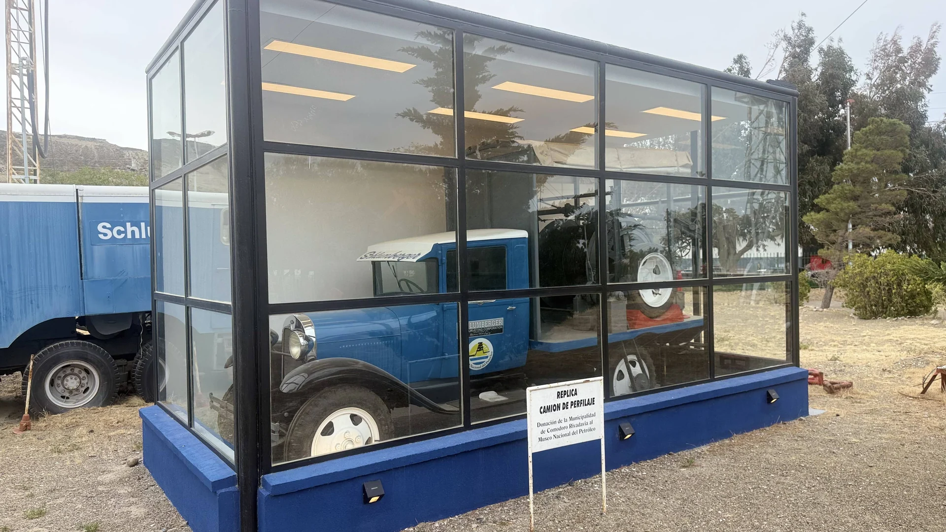 A blue historic oilfield truck replica displayed inside a glass enclosure at the Petroleum Museum