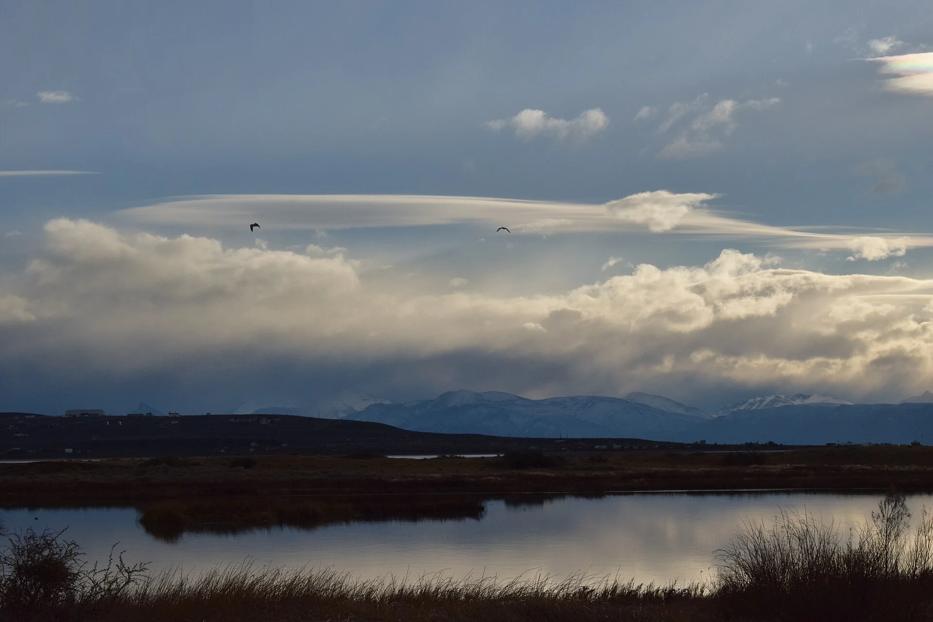 Water, reeds and mountains beneath a cloudy sky at Laguna Nimez