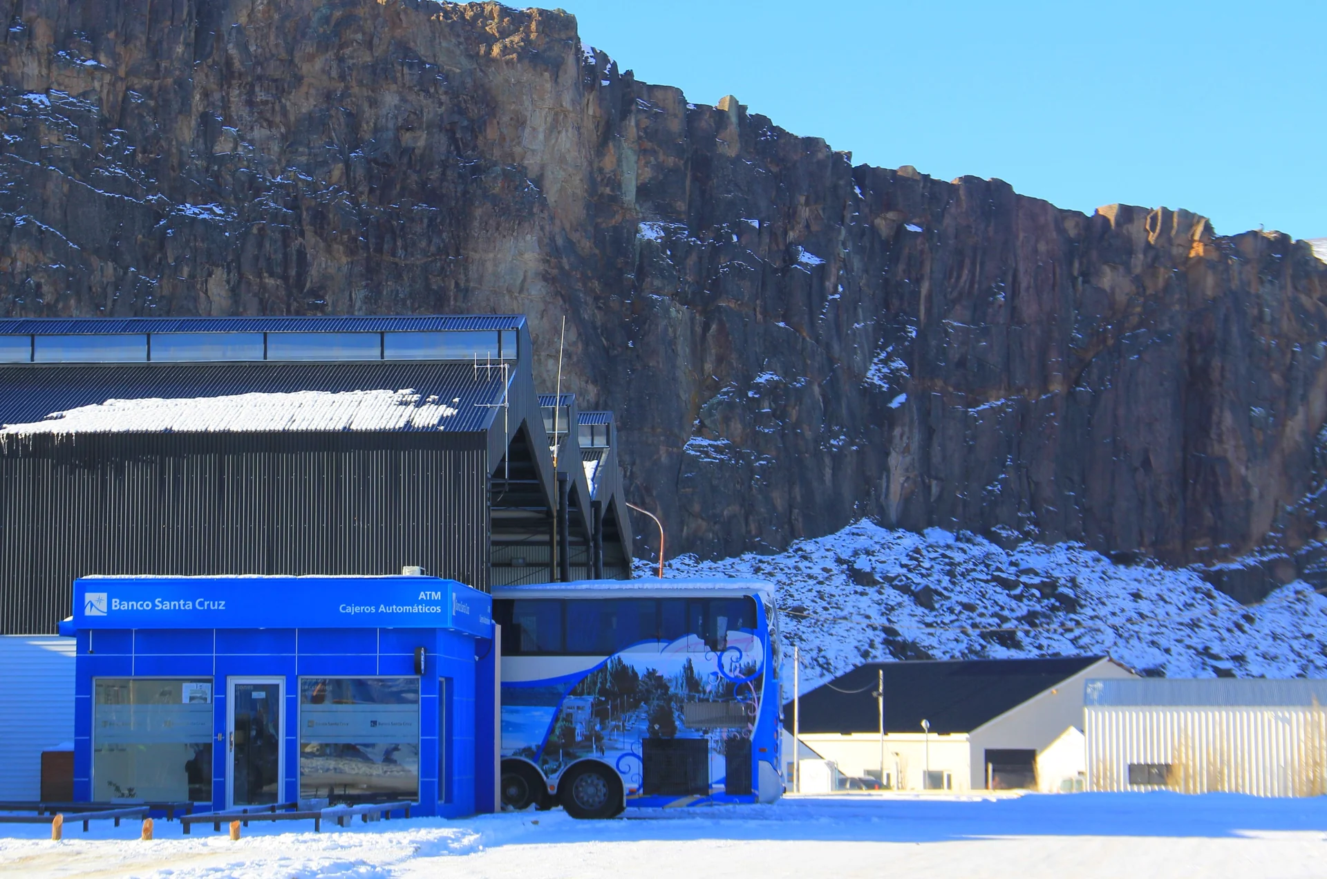 Snow around the El Chaltén bus terminal beneath a rocky hillside