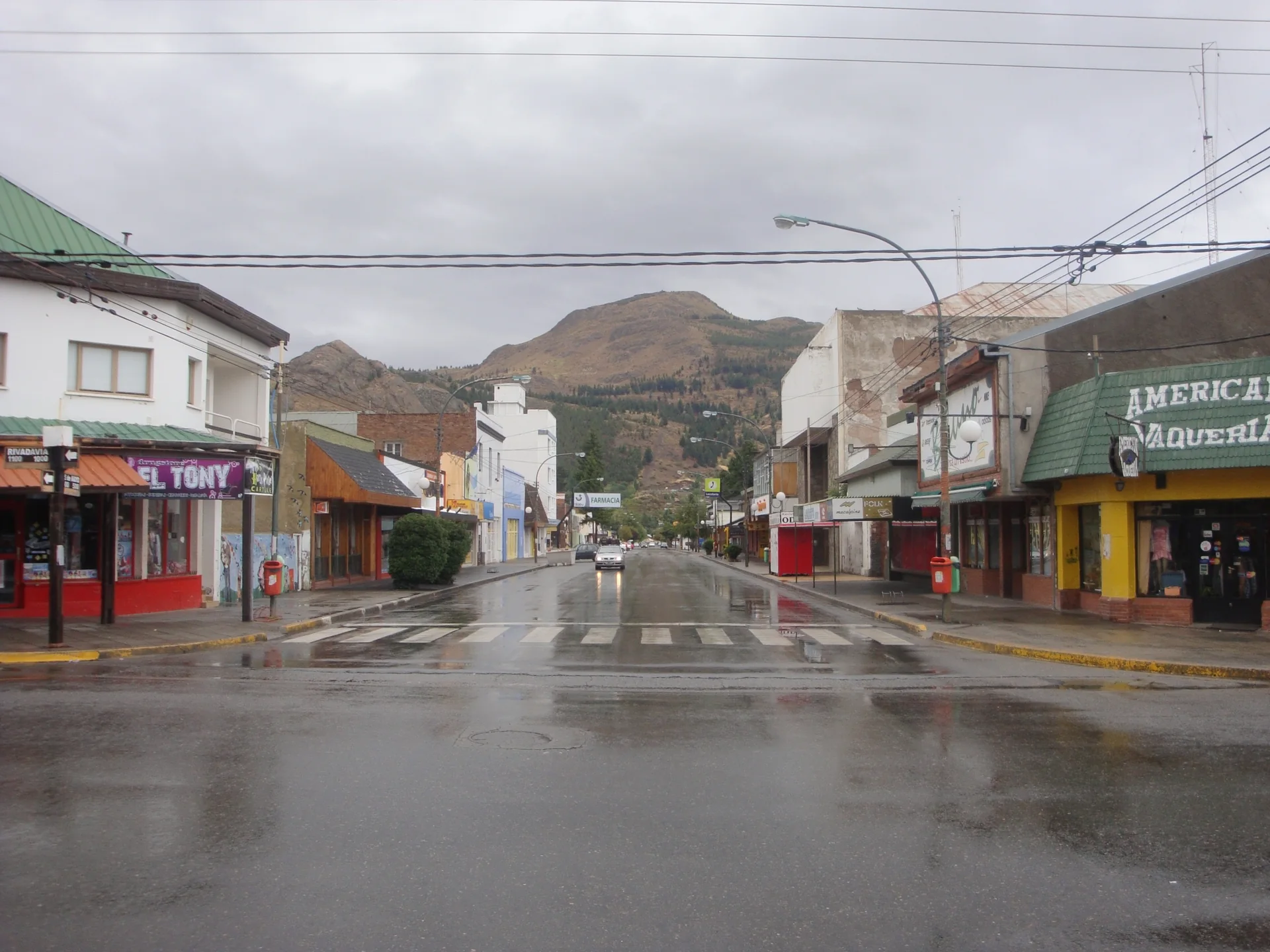 Shops and a wet street at Rivadavia and 25 de Mayo in Esquel