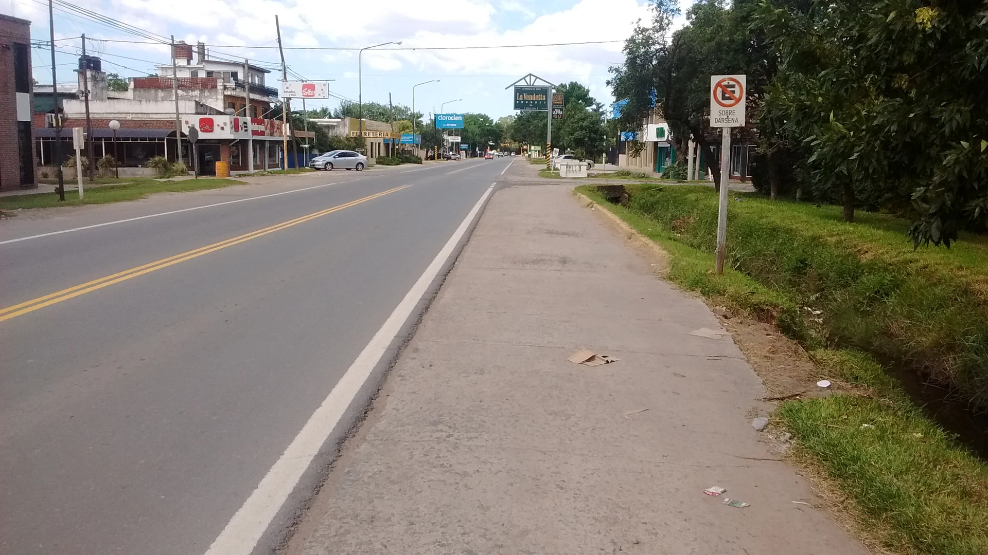 A paved commercial stretch of former Route 9 in Funes with roadside storefronts