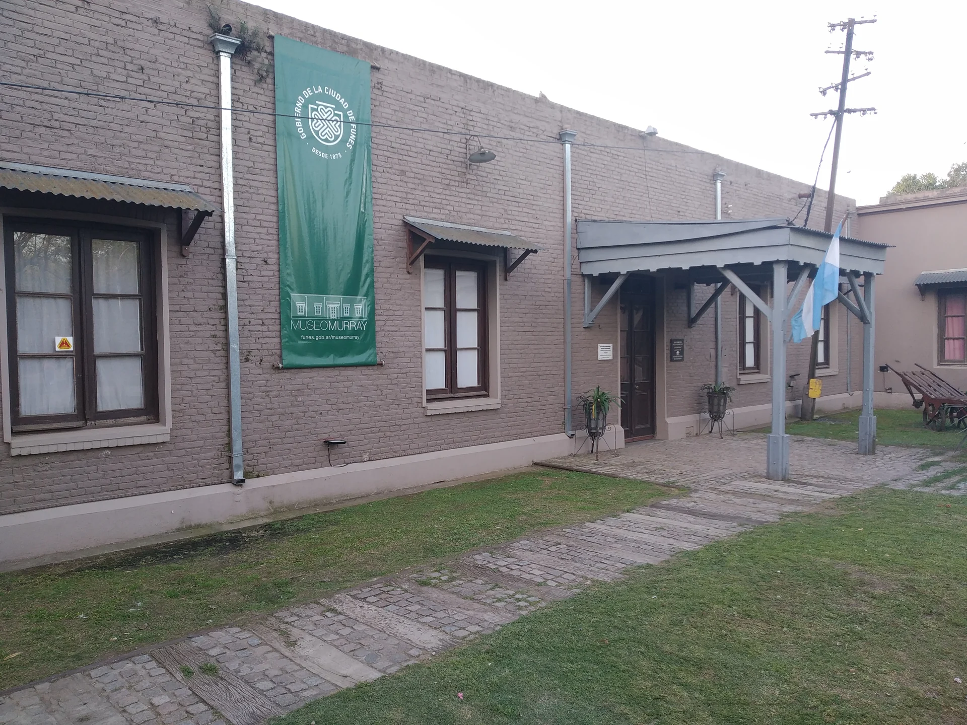 The brick former Funes station housing Museo Juan Murray, with flags and a museum banner