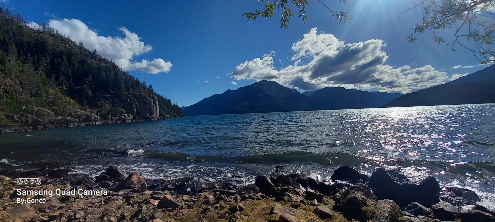Rocky Lago Puelo shoreline with turquoise water and forested mountains