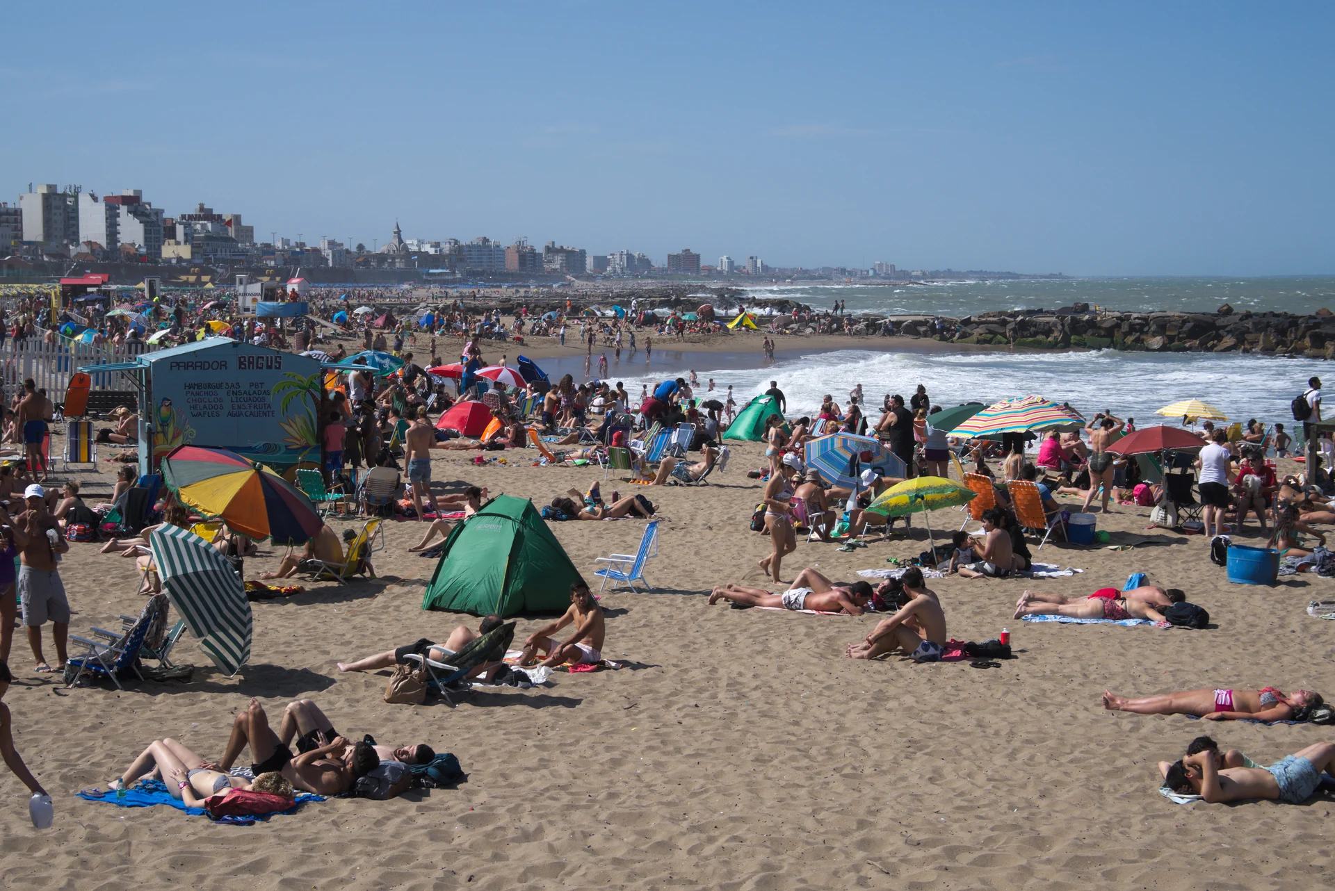 La Perla beach with swimmers, umbrellas, breakwaters and the Mar del Plata waterfront