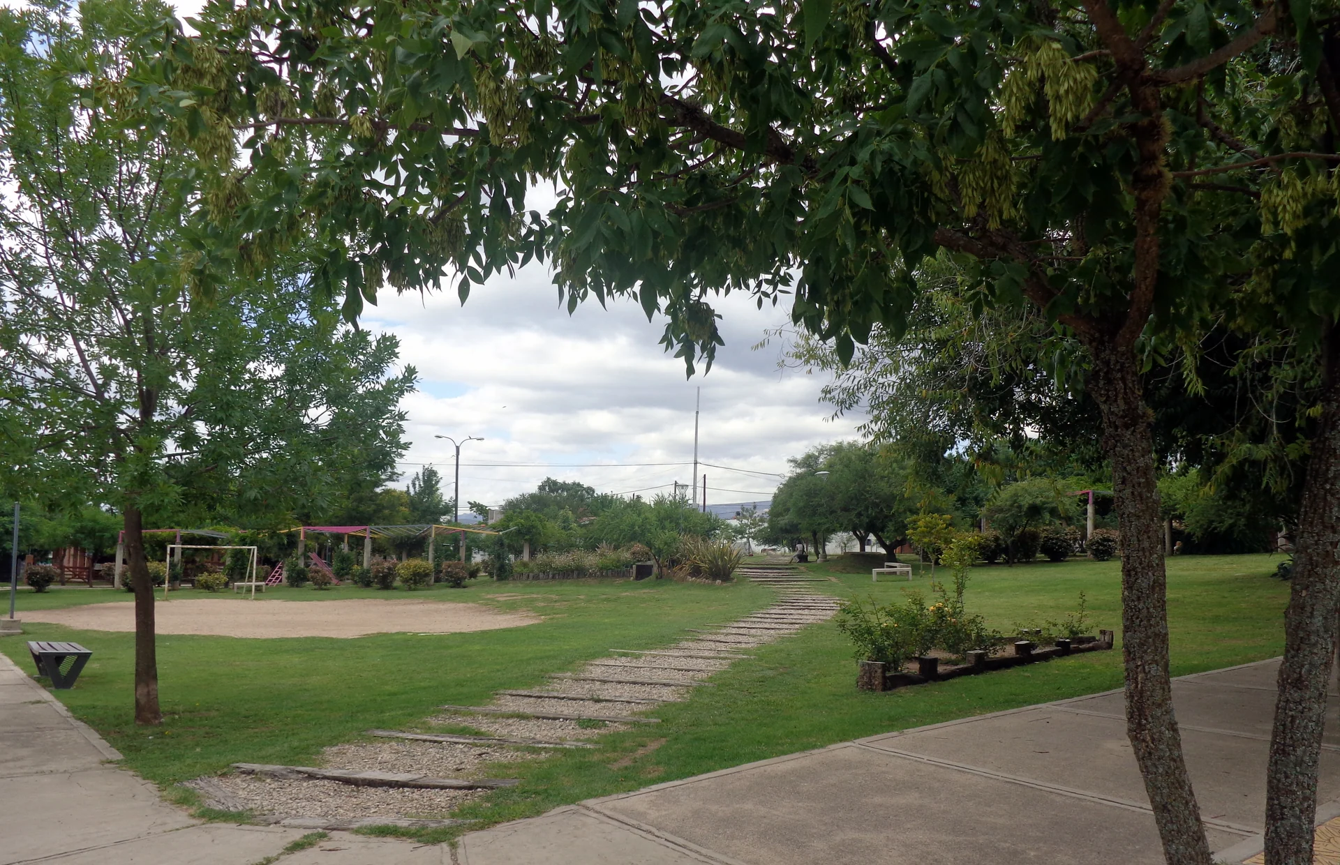 Tree-lined paths, grass and playground equipment at Plaza de los Niños in Mina Clavero