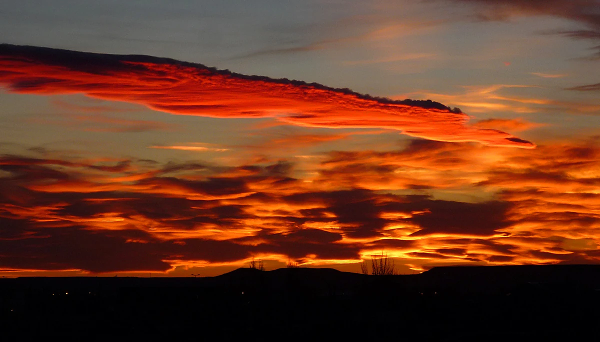 Orange sunset clouds above a dark silhouette of Río Gallegos buildings