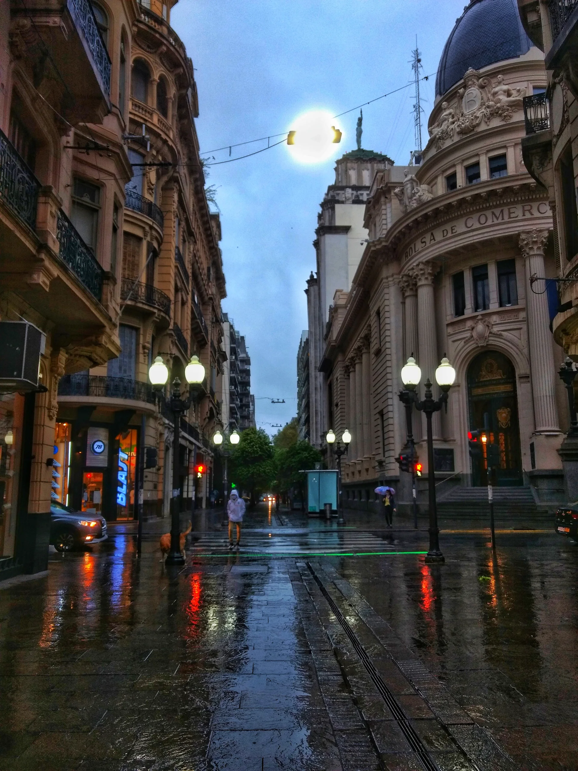 Wet pavement and pedestrians with an umbrella on Cordoba Street in Rosario