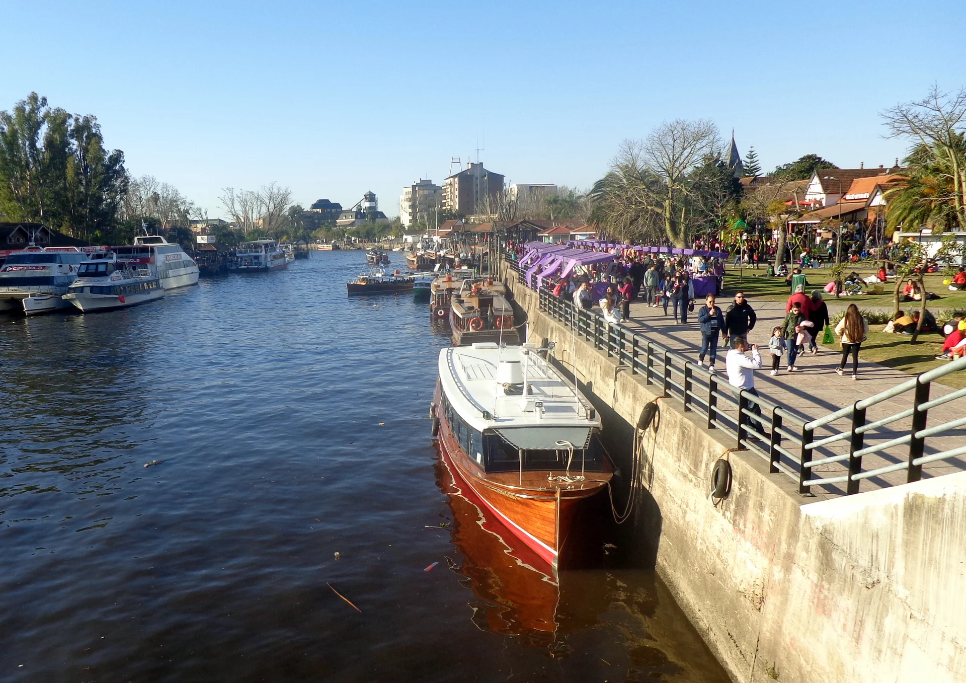 Passenger boats alongside Tigre’s fluvial terminal, with the river and people on the promenade