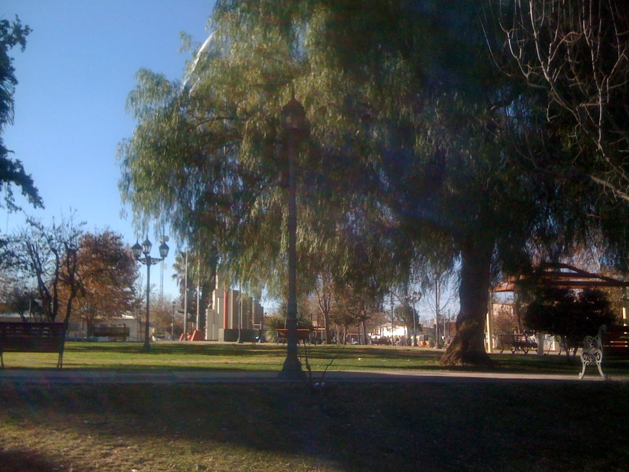 Trees, lawn, benches and a small pavilion in Tupungato’s town plaza