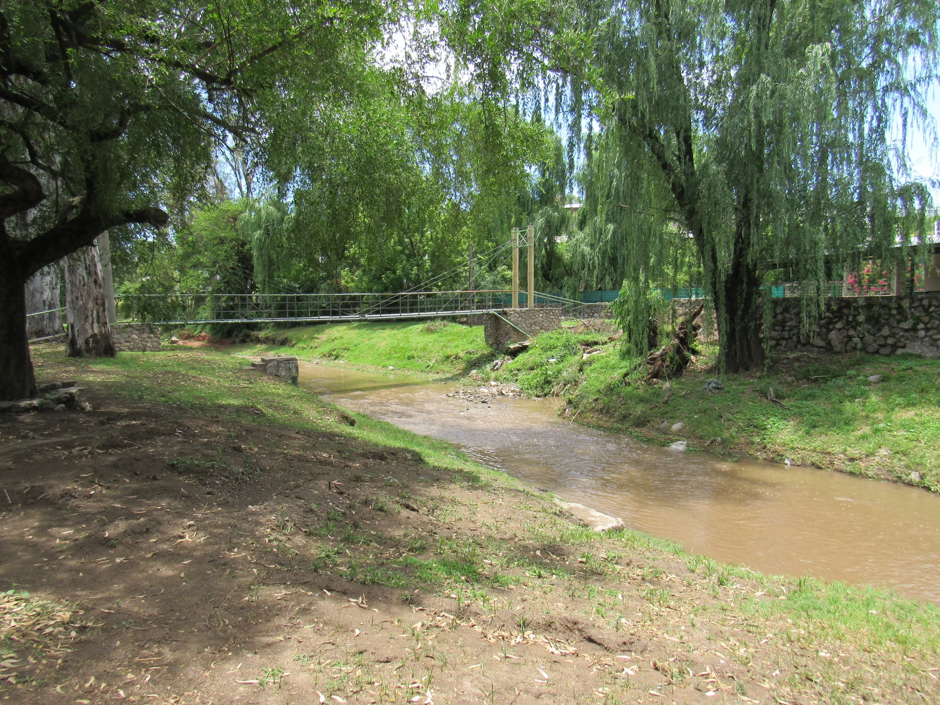 Tree-lined Arroyo Saldán and a footbridge in Villa Allende