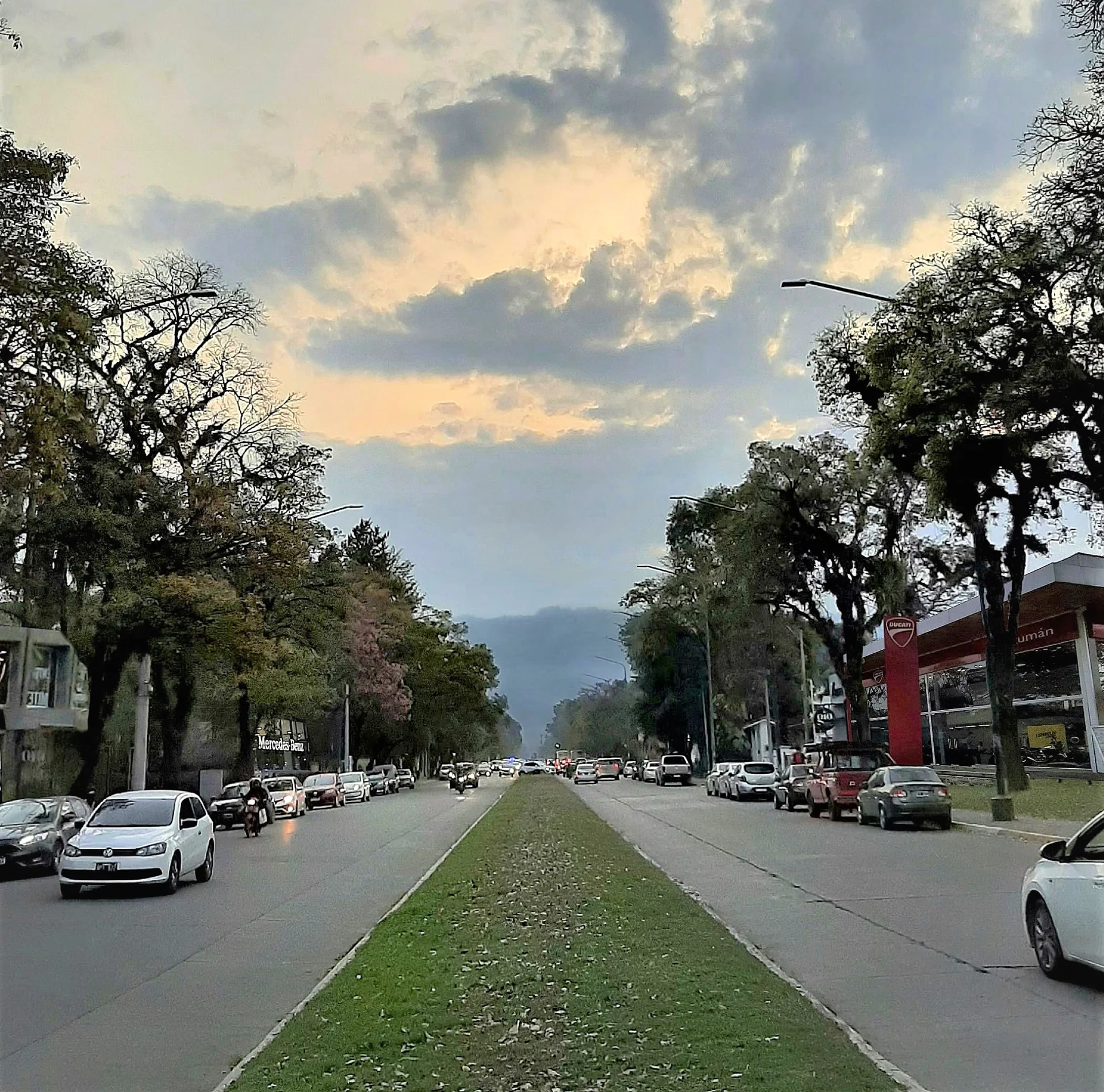 Tree-lined Avenida Aconquija with vehicles and a mountain backdrop in Yerba Buena